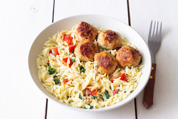 Orzo pasta with chicken meatballs, tomatoes and herbs. Italian food.