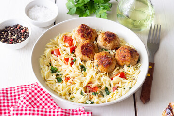 Orzo pasta with chicken meatballs, tomatoes and herbs. Italian food.