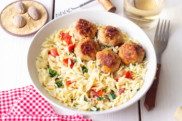 Orzo pasta with chicken meatballs, tomatoes and herbs. Italian food.