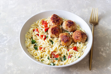 Orzo pasta with chicken meatballs, tomatoes and herbs. Italian food.