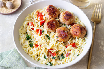 Orzo pasta with chicken meatballs, tomatoes and herbs. Italian food.
