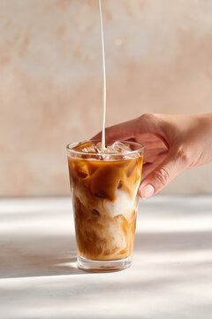 Chilled hojicha latte with ice and creamy plant-based milk in transparent glass on bright surface, Selective Focus..