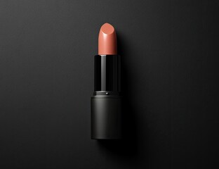 A nude-toned lipstick, dark-hued black case, isolated on a dark backdrop.  High-angle, studio shot of a cosmetic product.  The lipstick is a light brownish-pink. 