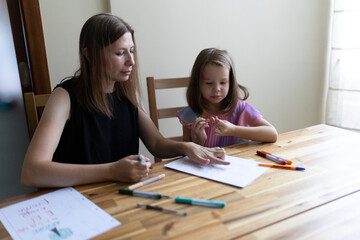 Mother helping daughter with homework, homeschooling, early childhood education