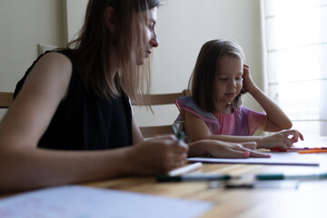Fototapeta premium Mother helping daughter with homework, homeschooling during quarantine