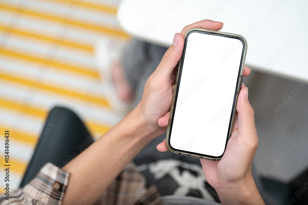 Poster close up of man hands holding white screen phone looking at feed or chatting in application on table