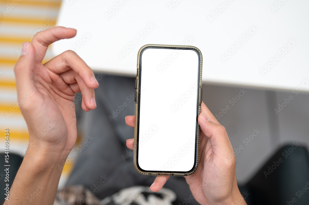 Poster close up of man hand holding blank screen phone looking at feed or chatting in application on table.