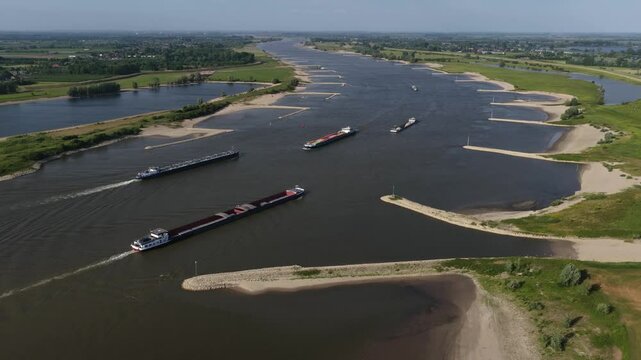 cargo ships on the Waal river, inland shipping industry, river barges, containers and bulk cargo. Aerial video.