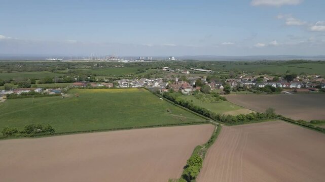 Arial view of Stogursey parish in the quantock hills Somerset. Drone moving to the left showing the village building and Hinkley point nuclear power station on the background. 4K, 60fps