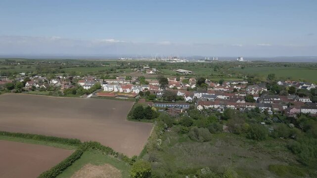 Arial view of Stogursey parish in the quantock hills Somerset. Drone moving to the left showing the village building and Hinkley point nuclear power station on the background.