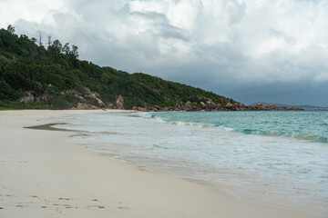 Dark storm clouds gather over a white sand beach on La Digue island in Seychelles
