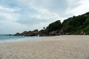 Granite boulders and dense tropical vegetation line the beach on La Digue island