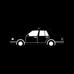 A black car with a white license plate. The car is parked on a black background