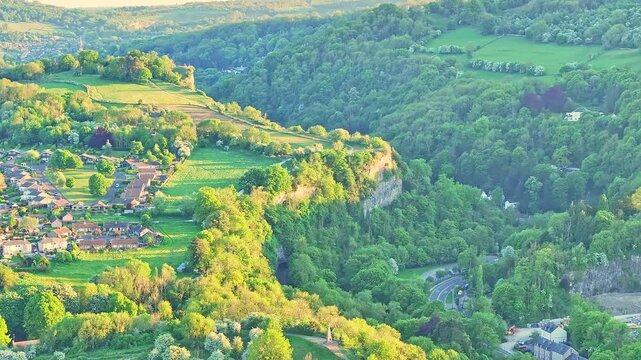 Aerial shot of Matlock Sparrow Park, Derbyshire, with dramatic limestone escarpment, dense woods, and homes near the River Derwent valley, highlighting English countryside and iconic cliff landscape