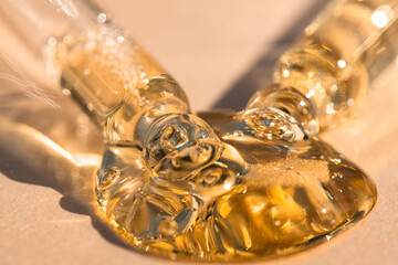 Pipettes with serum essential oil on beige background, front view, macro.