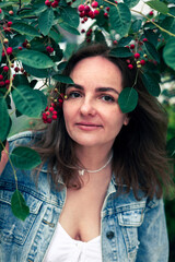 Portrait of a beautiful young woman with red berries in the park