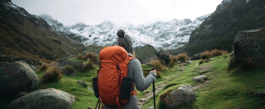 The woman with an orange backpack exploring a mountainous trail landscape - Powered by Adobe