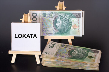100 Polish zloty (PLN) banknotes and the word “Lokata” (savings deposit) on miniature easels,...