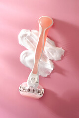 Women's razor and shaving cream on a pink background. Minimalist bathroom scene with soft light and pastel tones. High quality photo