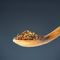 Aromatic spice mixture piled on rustic wooden utensil, great for gourmet cooking and flavor enhancement themes