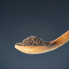 Brown cumin seeds in natural wood spoon, ideal for aromatic seasoning and exotic recipe preparation concepts
