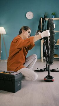 Woman with Toolbox Servicing Bicycle at Home Turning Wheels and Pedals