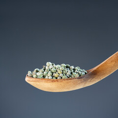 Organic green peppercorns arranged on wooden spoon, ideal for seasoning, cooking and culinary ingredient imagery