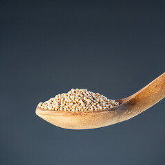 Dried whole pepper seeds displayed in rustic wood ladle, ideal for cooking ingredients and organic food photography
