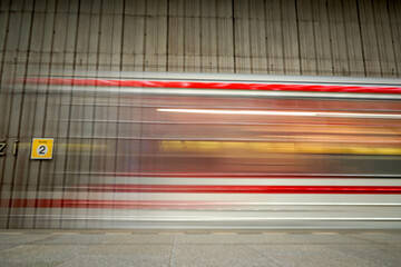 Motion blur of a subway train speeding past platform 2, capturing the sense of urban transit and...