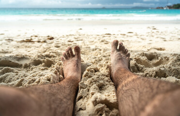 Bare feet resting in warm sand on tropical beach, symbolizing summer relaxation, freedom