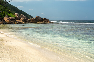 White coral beach with gentle entry into crystal-clear waters of the Indian Ocean