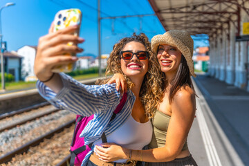 Two happy tourists taking selfie at train station platform