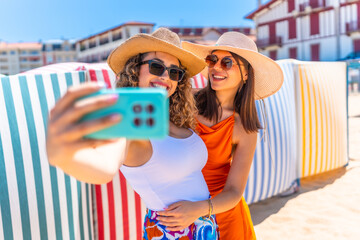 Two happy tourist women taking selfie on beach vacation