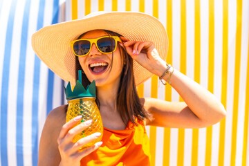 Happy tourist woman wearing sunglasses and sunhat drinking tropical juice at beach bar
