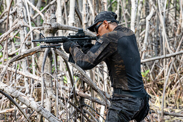military men in combat gear patrol in the middle of tropical jungle.