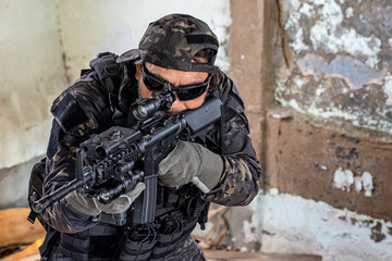 infantryman in military uniform shooting with weapons and rifles at abandoned demolished building.