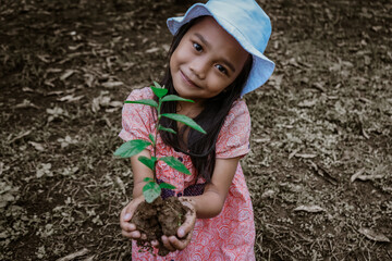 little girl planting trees in a barren forest