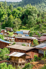 Obraz premium Traditional hill tribe village surrounded by lush rainforest in northern Thailand. Wooden stilt houses under tropical canopy in a peaceful mountain valley near Chiang Mai.