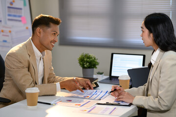 Two business colleagues discussing financial reports during a meeting at the office