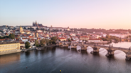 The morning light casts a warm glow over Prague, illuminating the Vltava River and the historic...