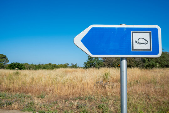 Electric car charging unit with blue screen in open countryside, clear blue sky and green energy infrastructure aligned in composition