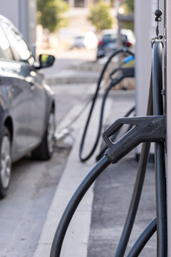 Row of parked electric vehicles connected to charging units, clean energy transition in urban mobility infrastructure, captured in a Spanish parking lot