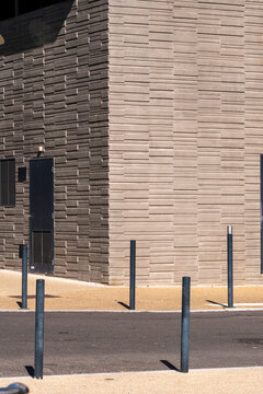 Textured stone facade with bollards and sidewalk space, modern urban material and clear visual area for message placement