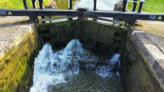 Lock gate releasing powerful water flow. Sluice system adjusting canal water levels. Hydraulic barrier managing cascading current. Navigational lock regulating passage between sections