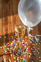 glass of champagne, deflated balloon, confetti on table
