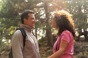 Happy mature couple smiling and talking face to face on a romantic hike in a forest