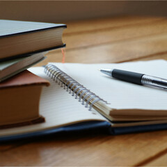 There are books, a notebook and a pen on the table