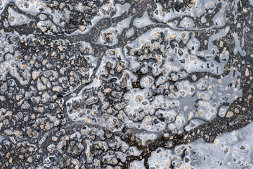 Water pooling on textured asphalt creates mesmerizing natural patterns