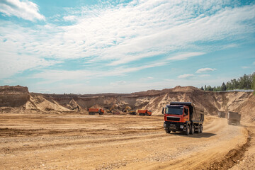 A loaded car drives out of a sand quarry. Sunny weather and clear skies