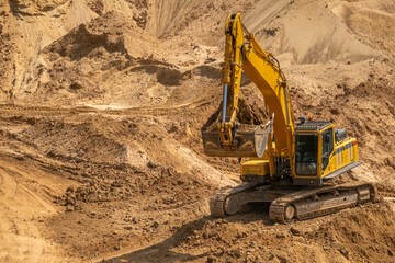 A caterpillar tractor works with a bucket in a sand pit. Sand mining
